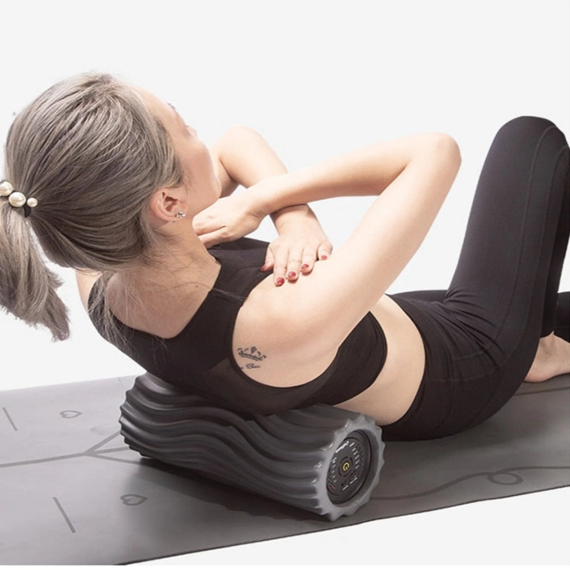 Woman using pro vibration foam roller on upper back muscles for deep tissue recovery and muscle tension relief
